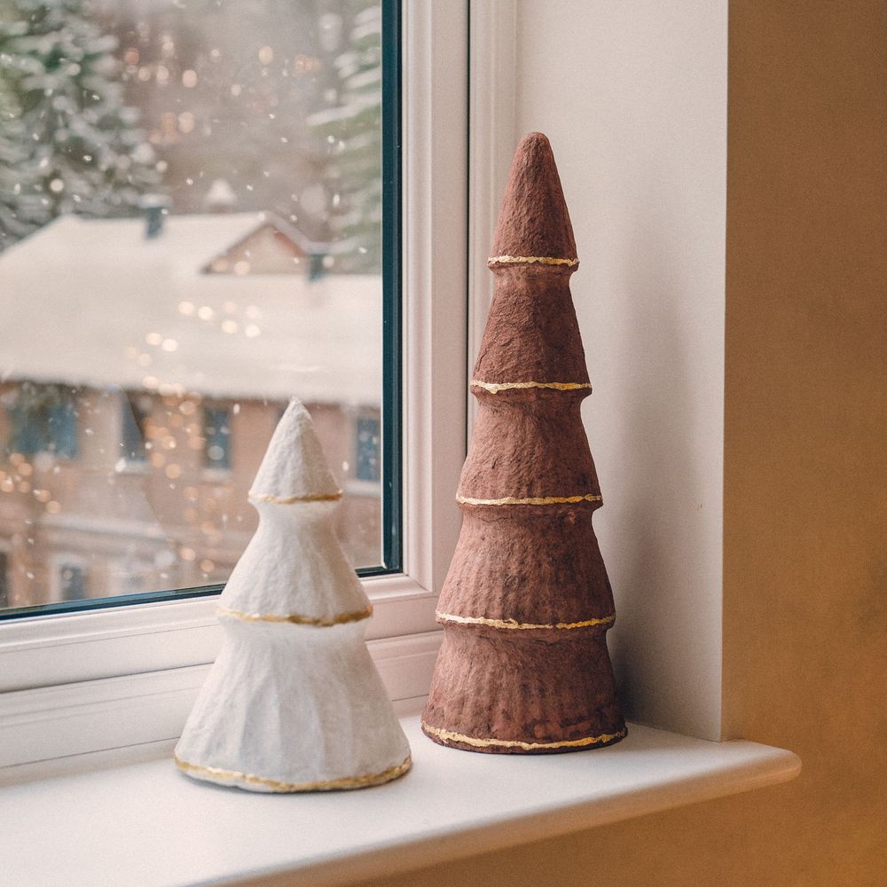 Lifestyle brand photography of decorative ceramic Christmas trees on a window sill