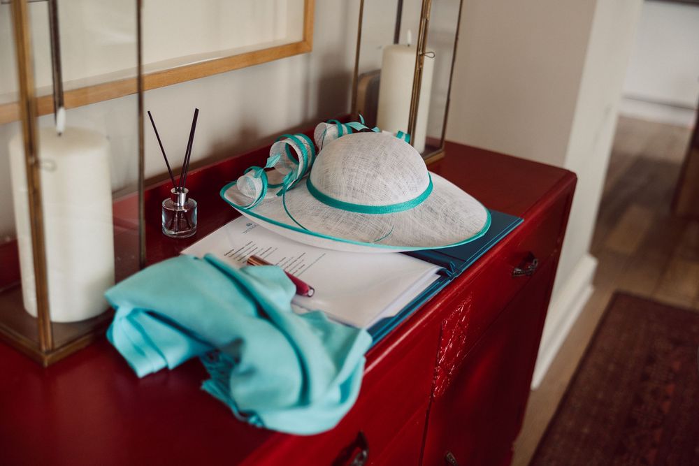 A turquoise and white colored dress hangs on a mannequin in a boutique display with red walls.