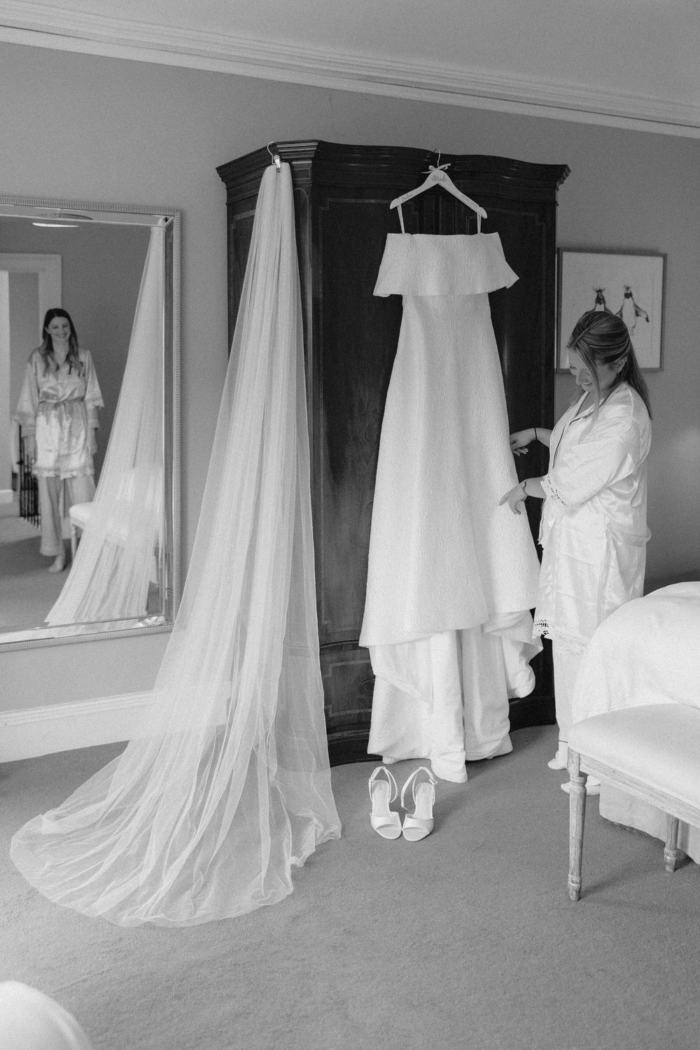 A collection of white wedding dresses and gowns hanging in a row against a wall in a bridal shop.