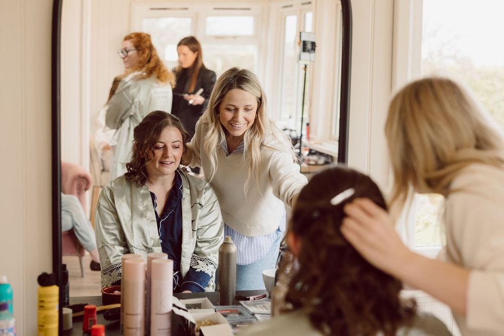 Stylists work together in a bright salon space with hair products and styling tools on the counter.