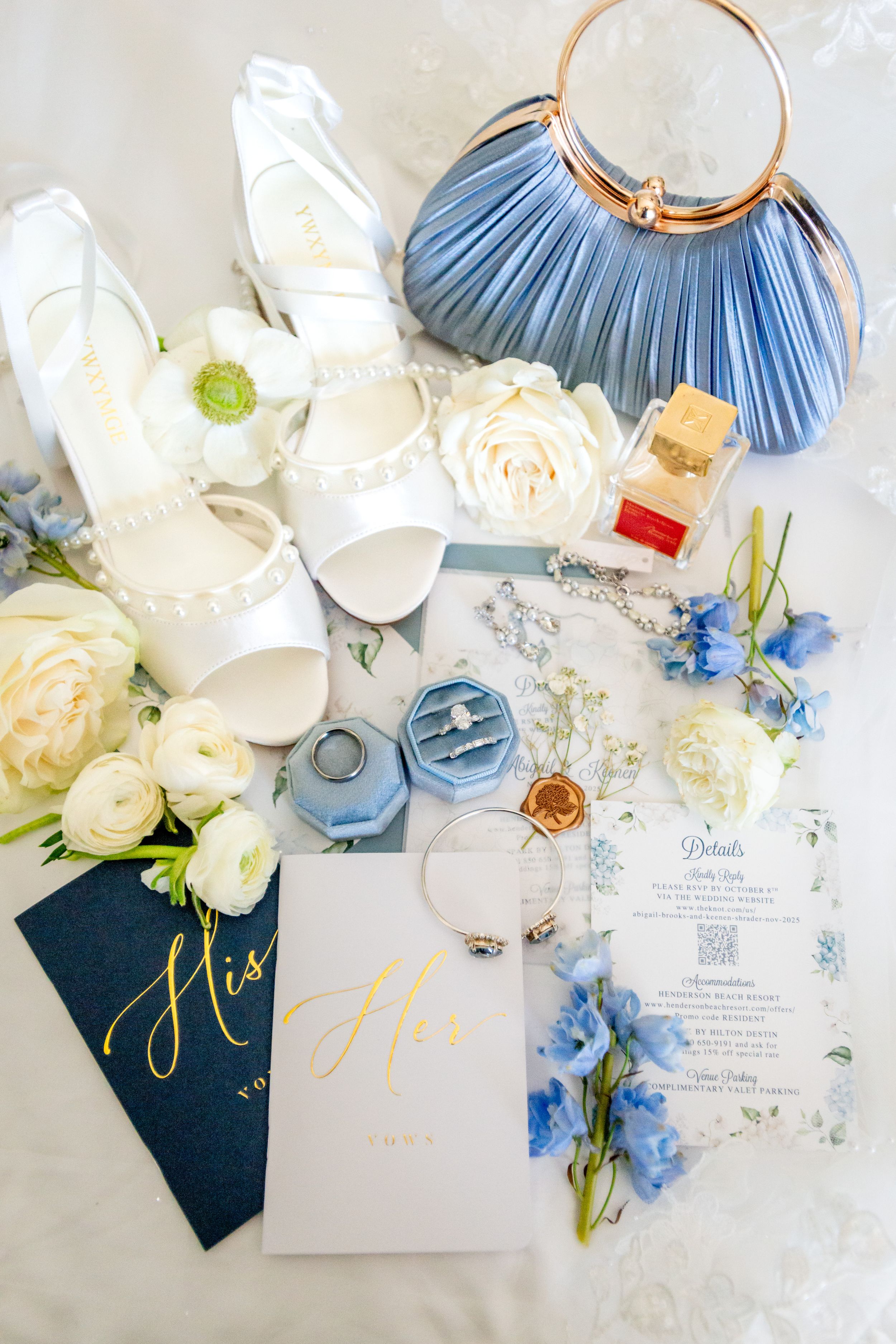 Wedding stationery flat lay with blue and white flowers, invitations and delicate details.