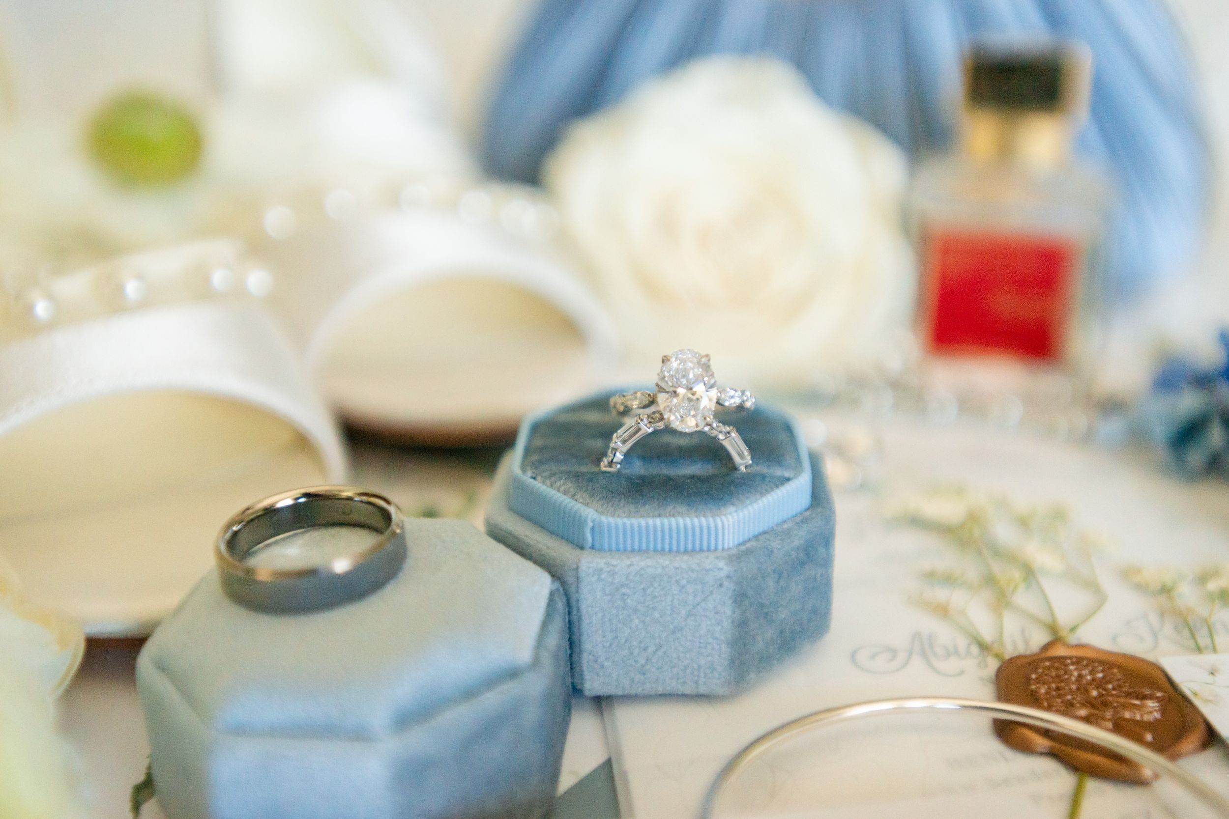 Wedding accessories including rings and jewelry arranged on light blue fabric.