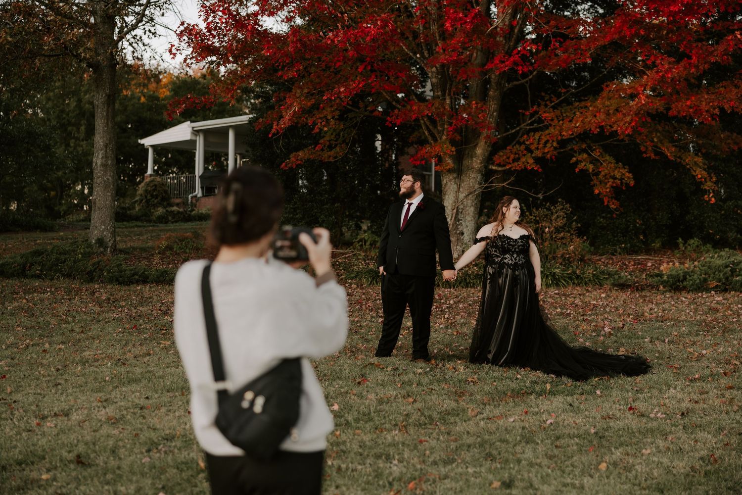A romantic autumn wedding scene with red and orange fall foliage in the background.