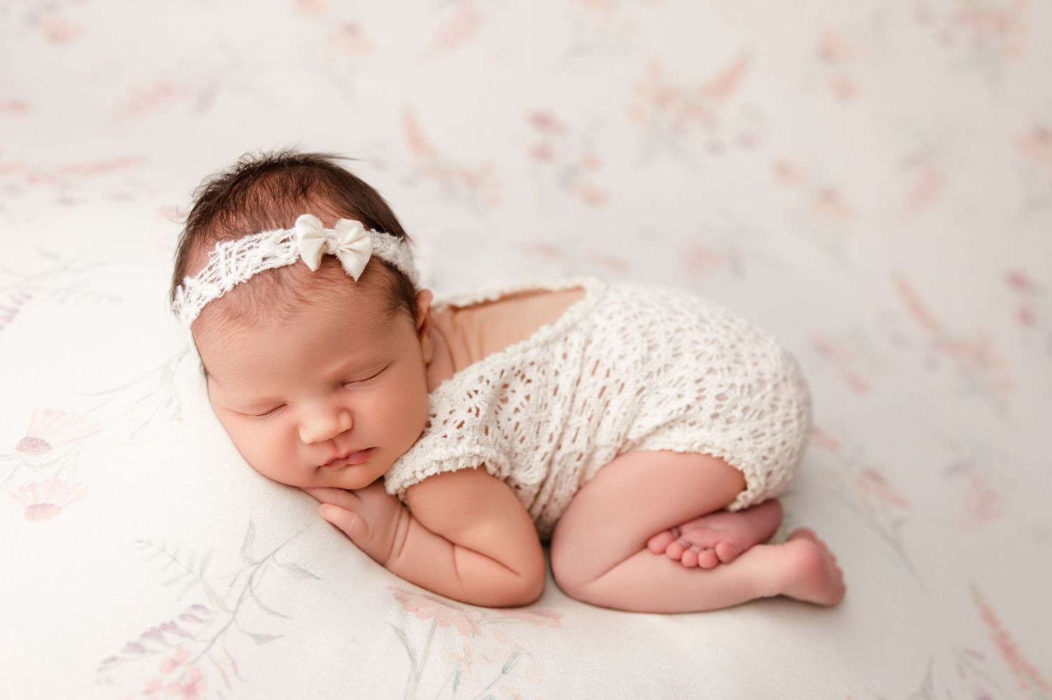 Newborn baby peacefully sleeping during professional newborn photography session on floral backdrop