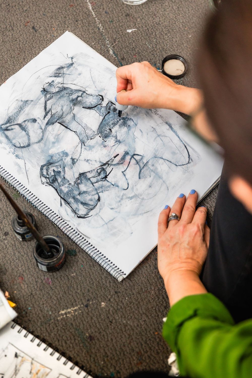 Artist creating expressive ink drawings in sketchbook with fluid brushstrokes and dark tones.