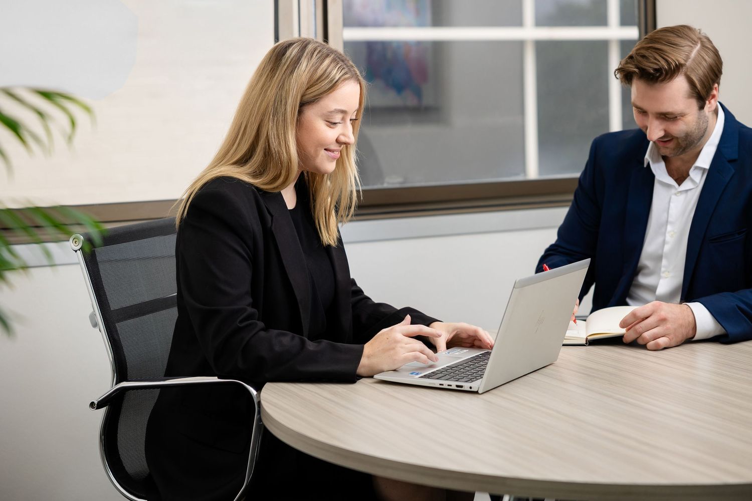 Business professionals collaborate at a modern office desk with laptops and documents during a meeting.
