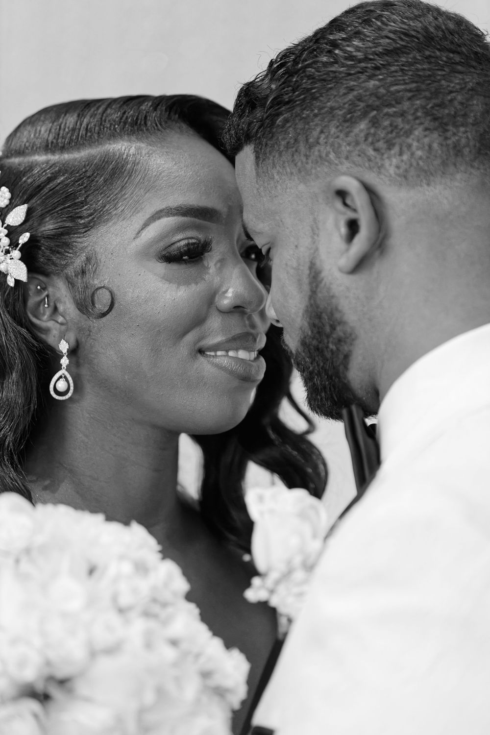 A black and white close-up of a smiling bride and groom sharing a tender moment.