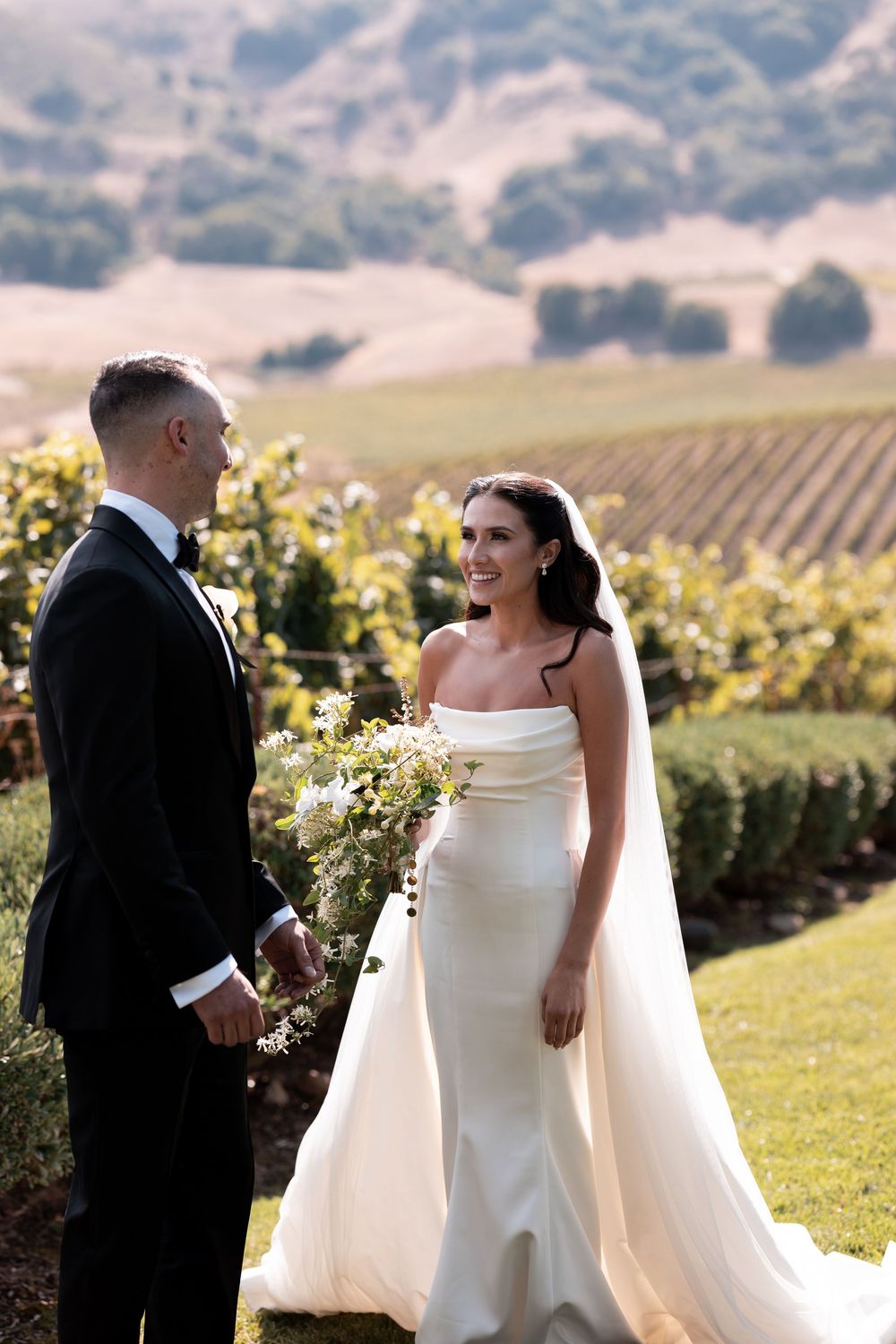 A couple shares intimate moments during their wedding photoshoot in a sun-drenched vineyard setting.