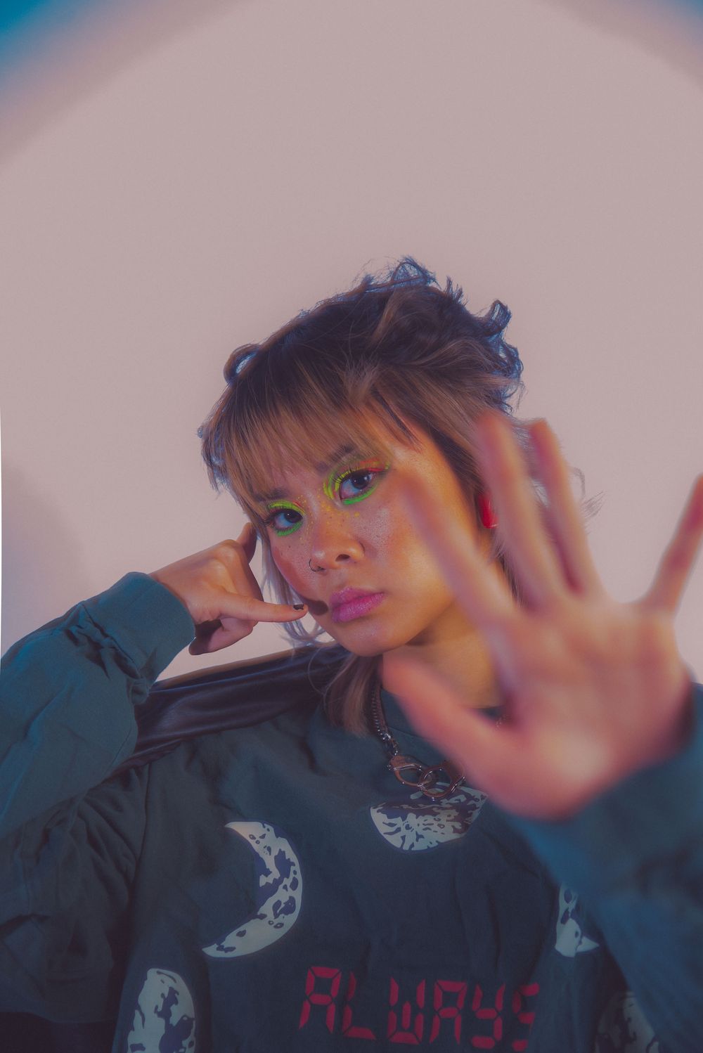 Person in dark jacket with hand raised in front of camera.