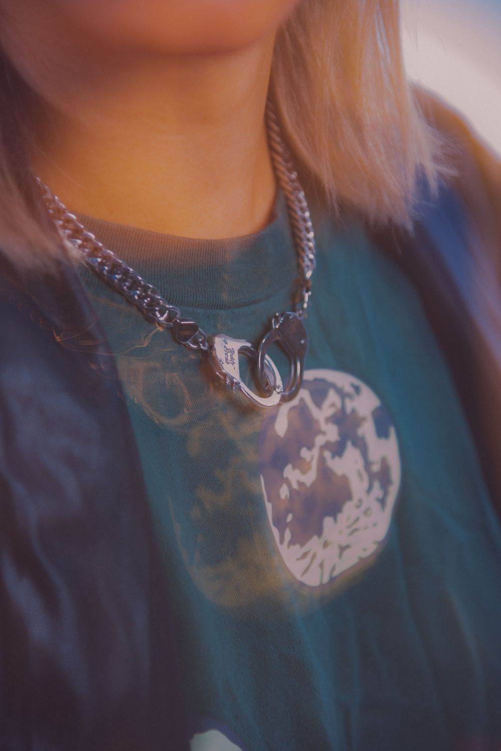 Close-up shot of a silver chain necklace against a dark teal sweater.