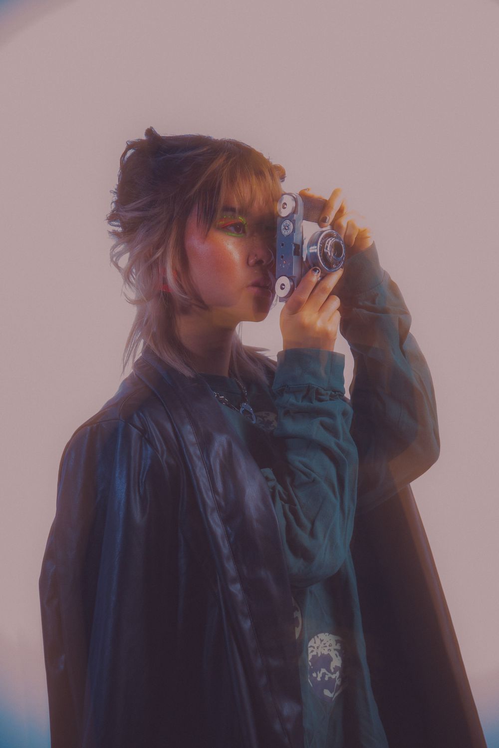 Side profile of someone holding a camera in a dark teal jacket.