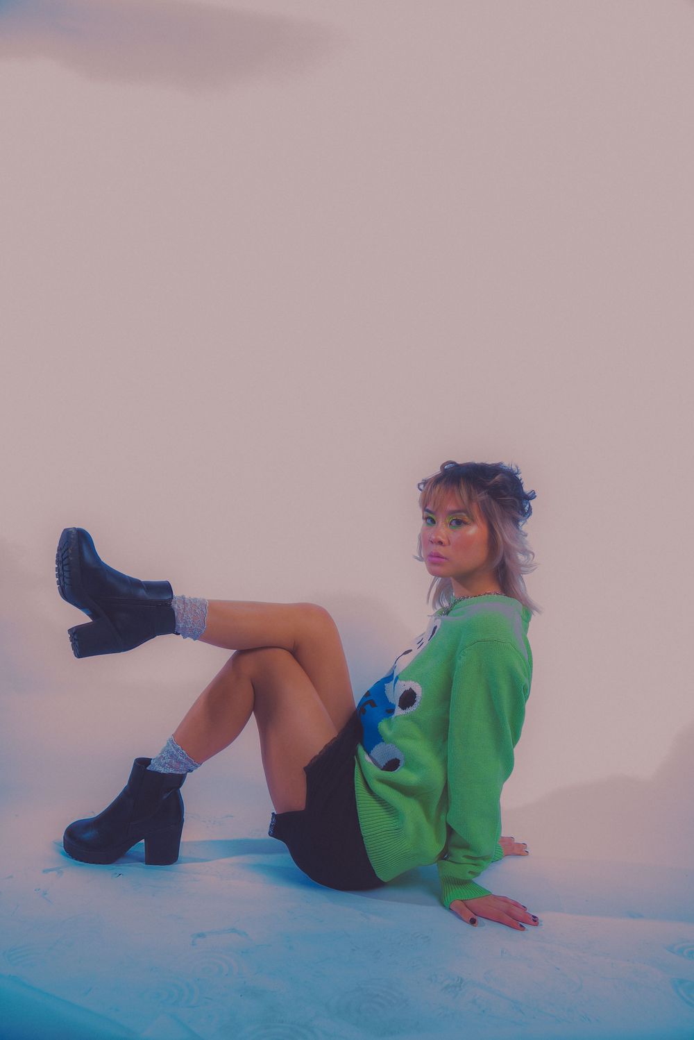 Fashion model pose on white background wearing green sweater and black boots.