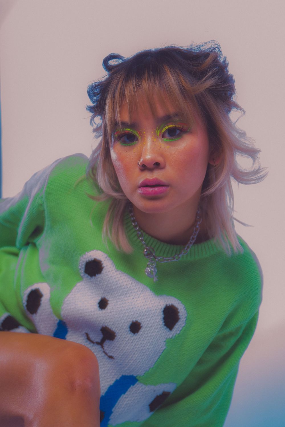 Person wearing a bright green sweater with white and blue graphic design.