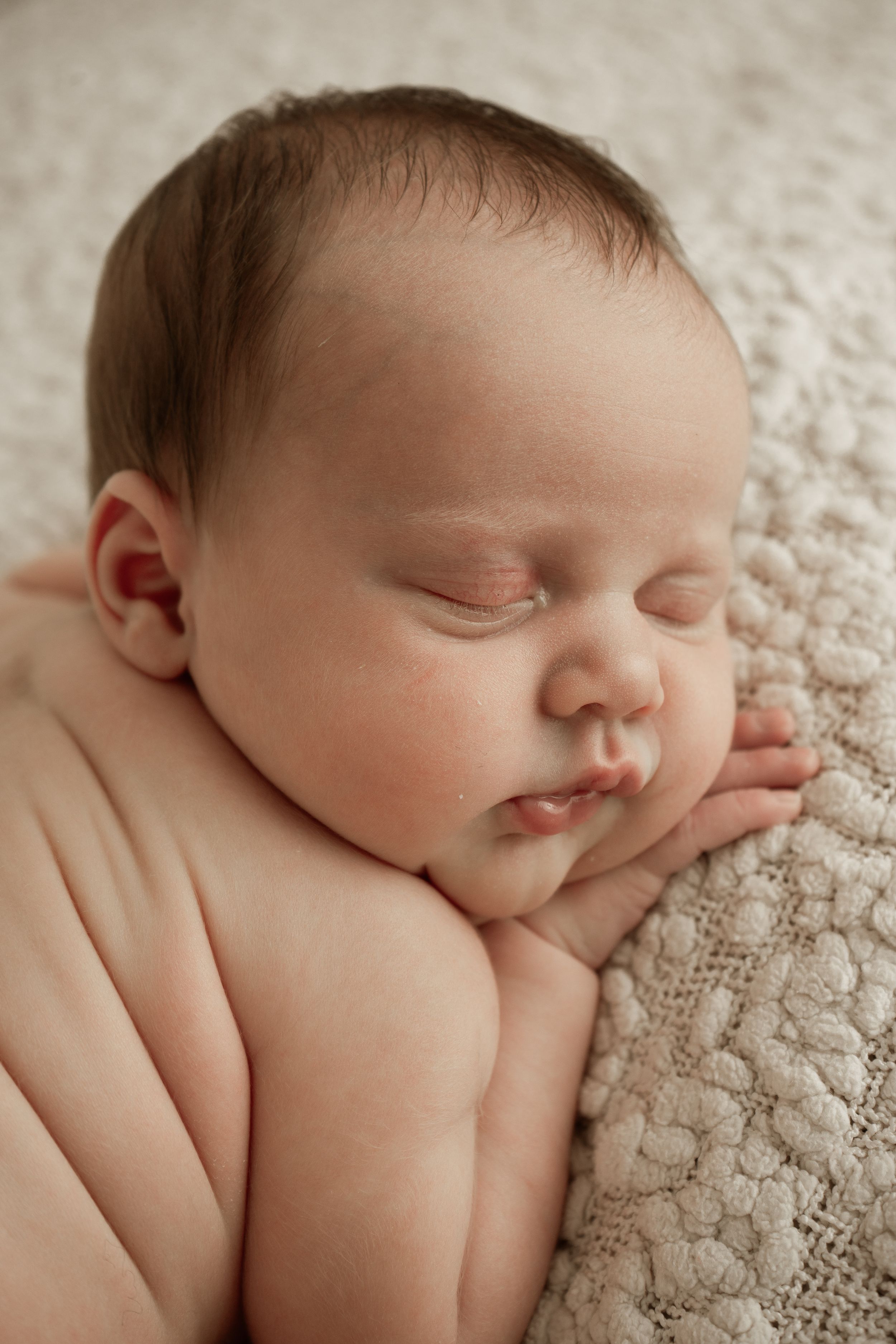 A series of close-up photos showing a sleeping newborn baby resting peacefully on textured cream-colored fabric.