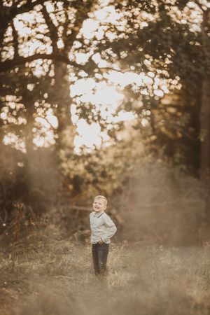 A dreamy sunset photoshoot in a misty forest with golden light filtering through the trees.