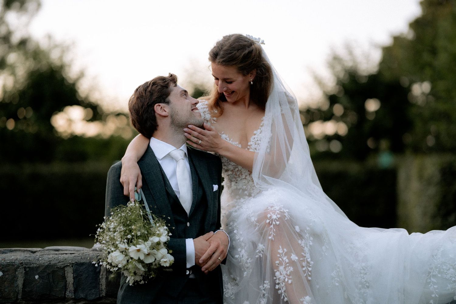 A romantic wedding couple shares intimate moments in a garden setting during golden hour.