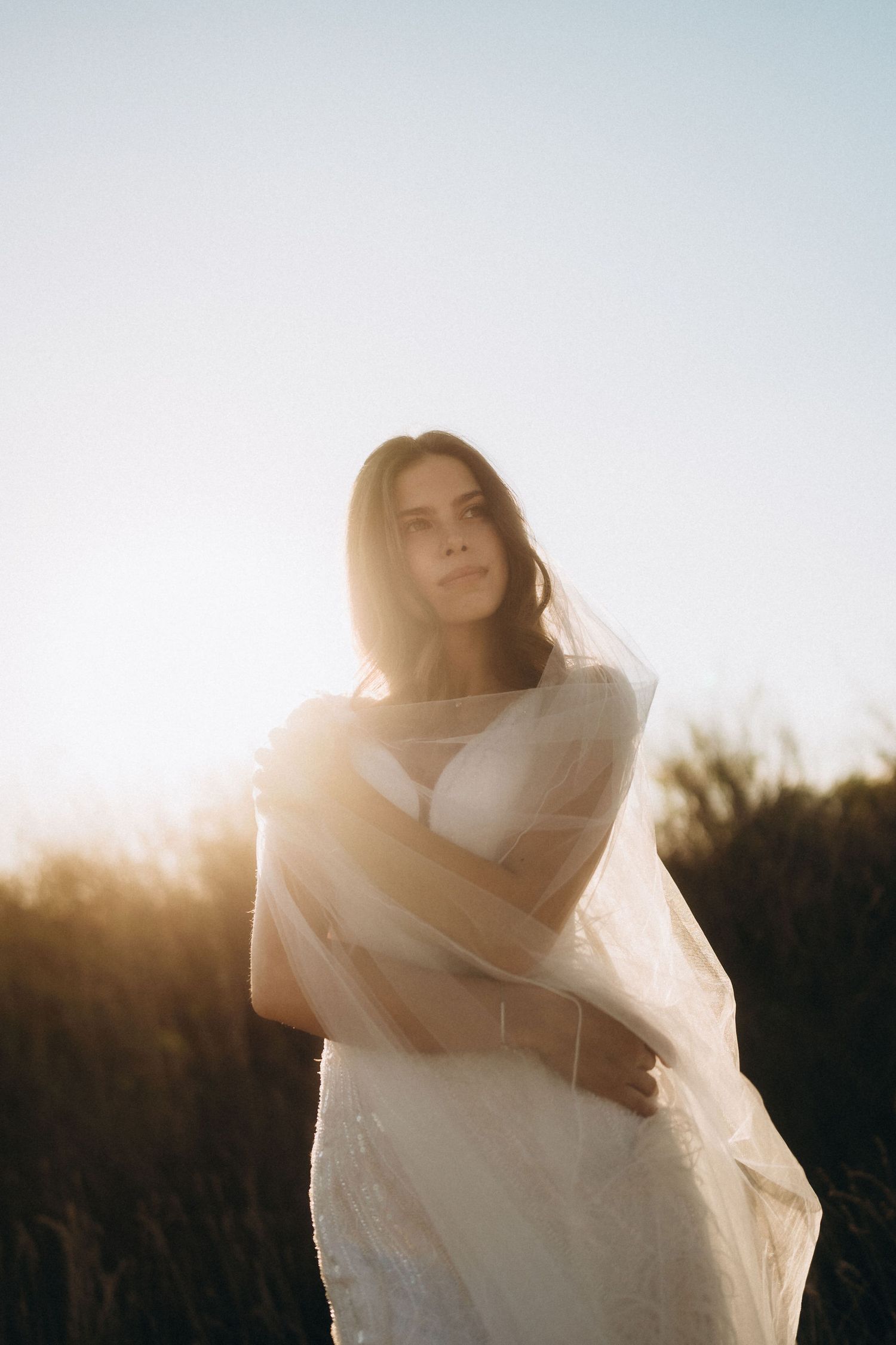 Ethereal portrait series of a person wrapped in white fabric against sunset light.