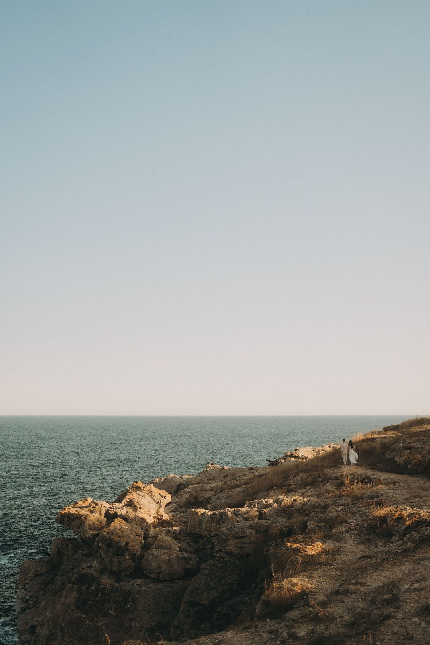 Scenic coastal landscape with rocky cliffs overlooking vast ocean at golden hour.