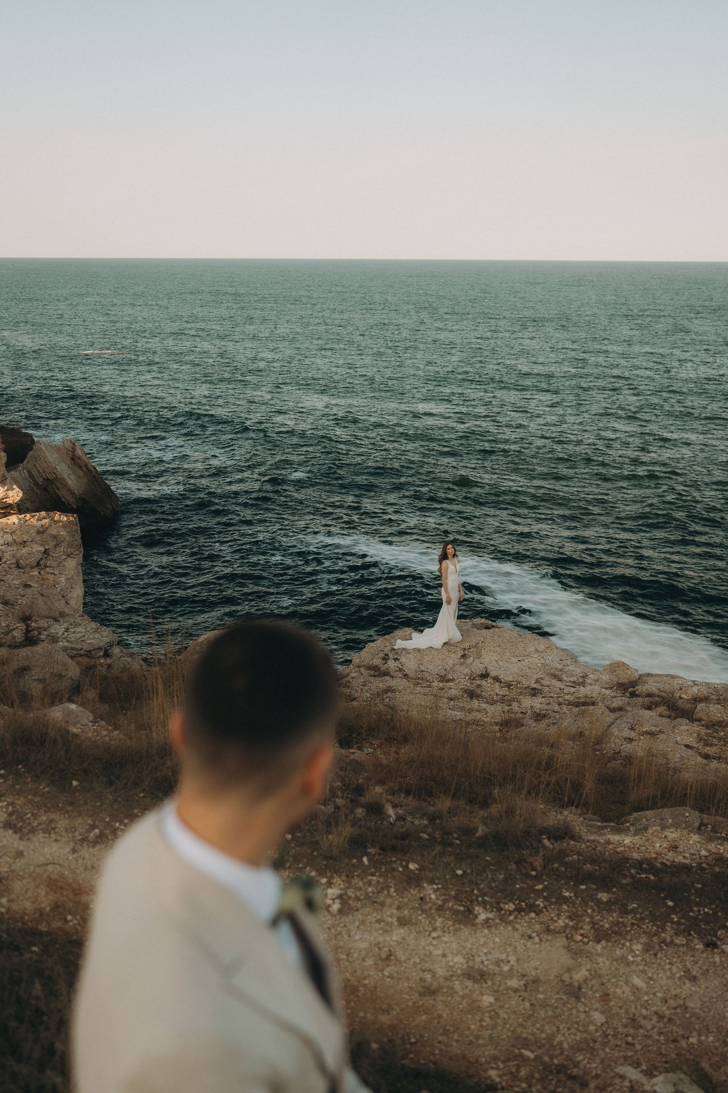 Wedding photography session on rugged coastal cliffs with deep blue ocean waters in the background.