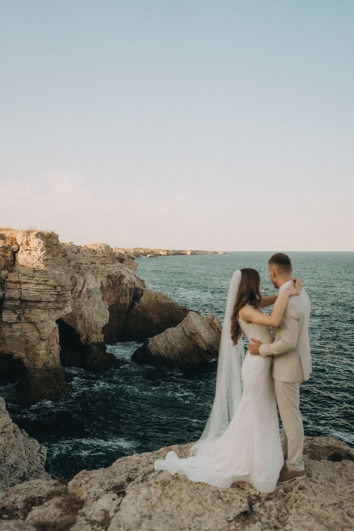Romantic wedding photoshoot on dramatic limestone cliffs against a serene ocean backdrop.