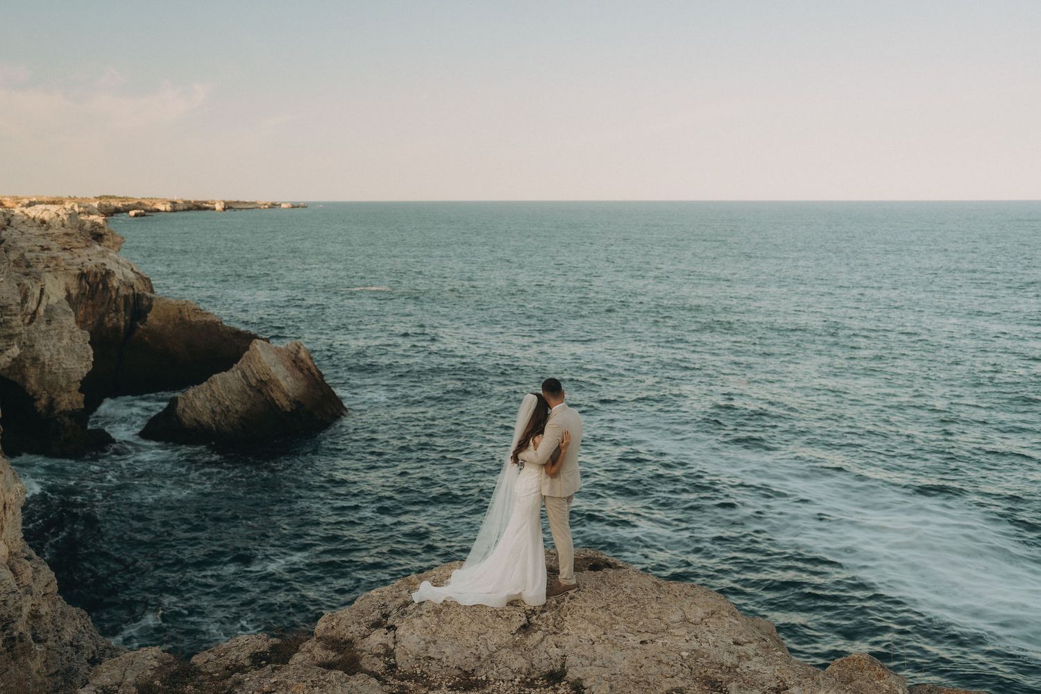 Scenic wedding photos captured on rugged seaside cliffs during golden hour.