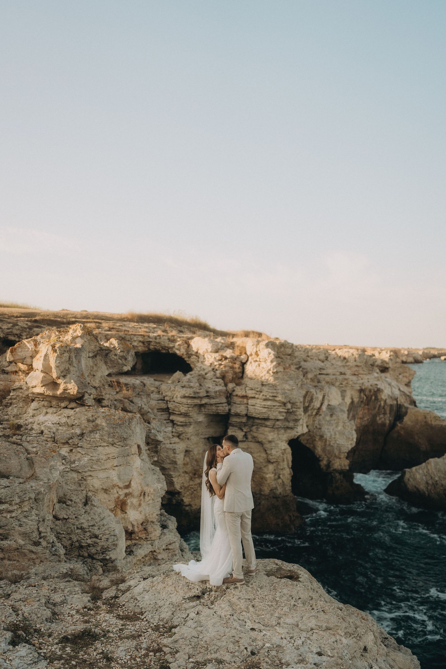 Dramatic wedding portraits taken on limestone cliffs against the backdrop of crashing waves.
