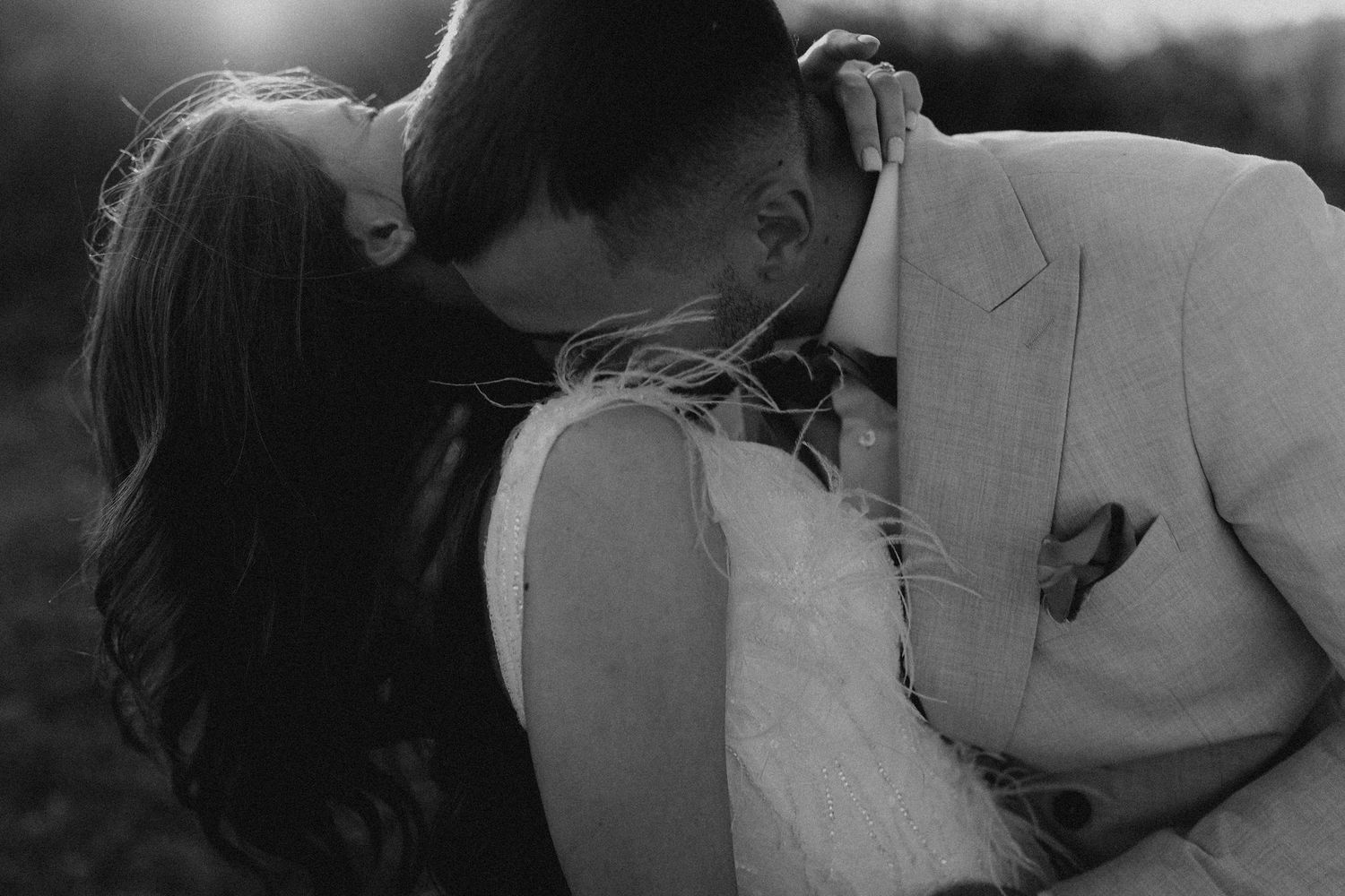 Black and white wedding portrait capturing an intimate moment at sunset.
