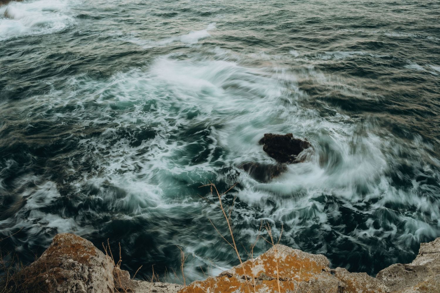 Dramatic ocean waves crash against rocky cliffs creating white water patterns.