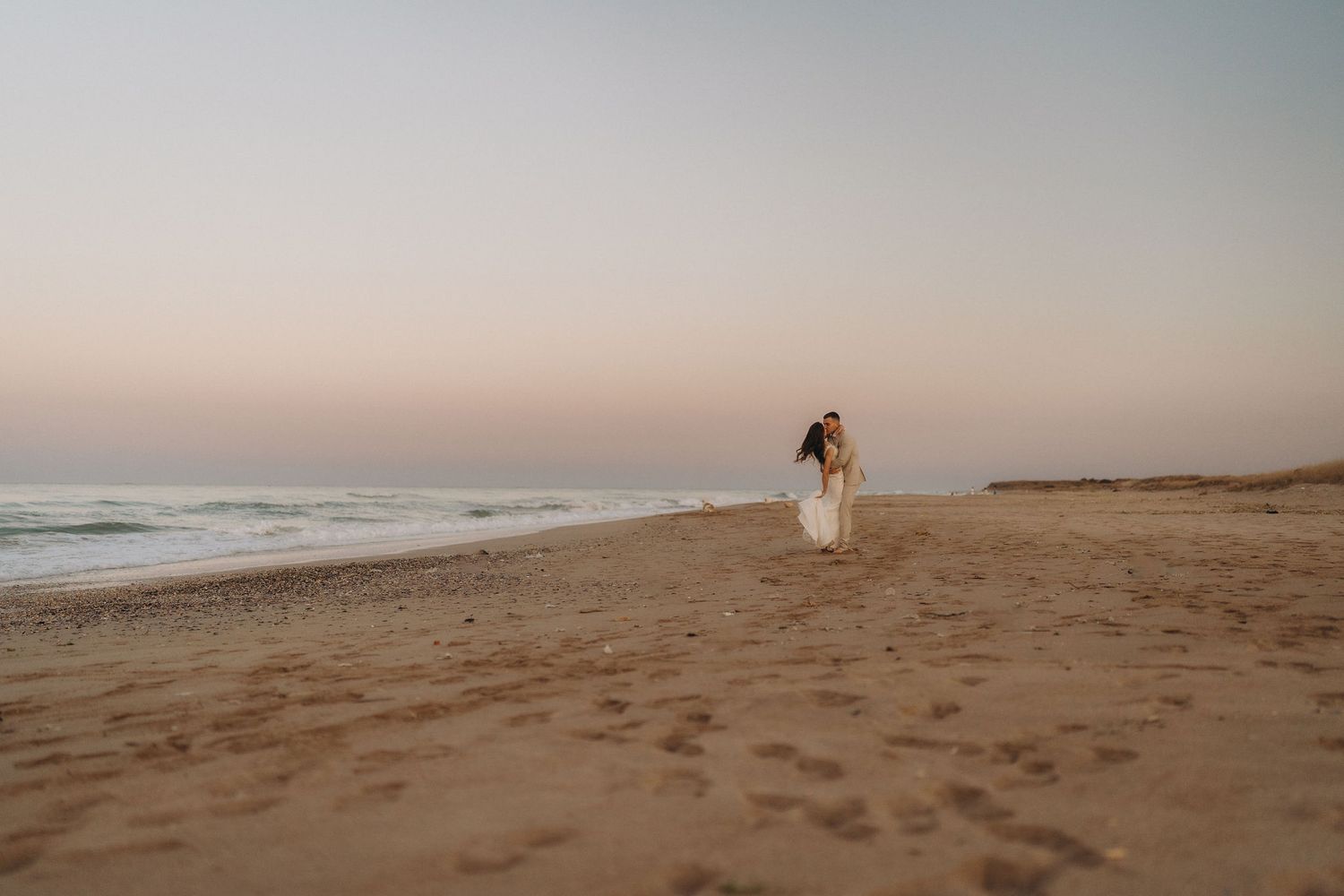 A serene empty beach stretches into the distance during golden hour.