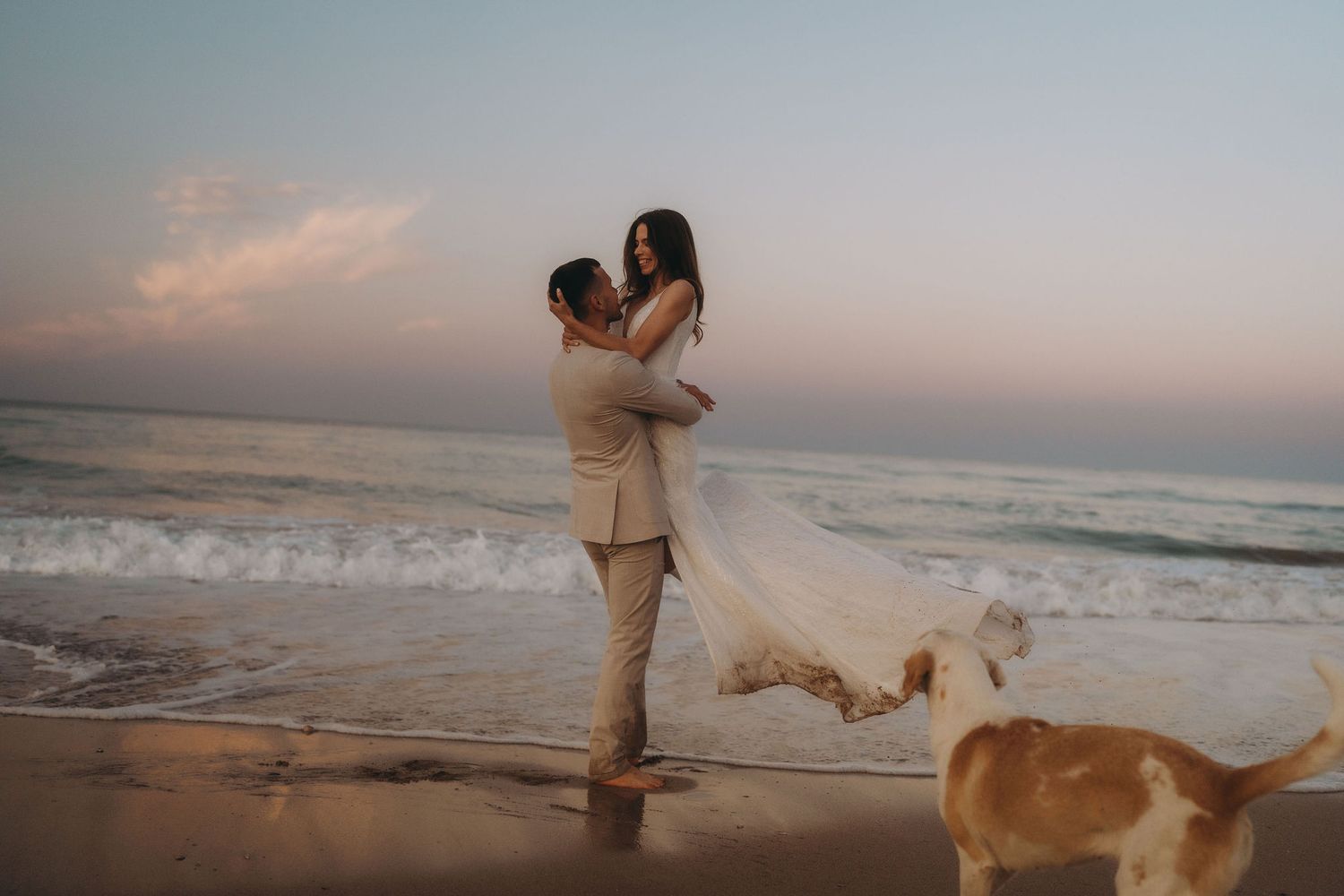 A romantic beach photoshoot with a couple and their dog enjoying the sunset by the ocean.