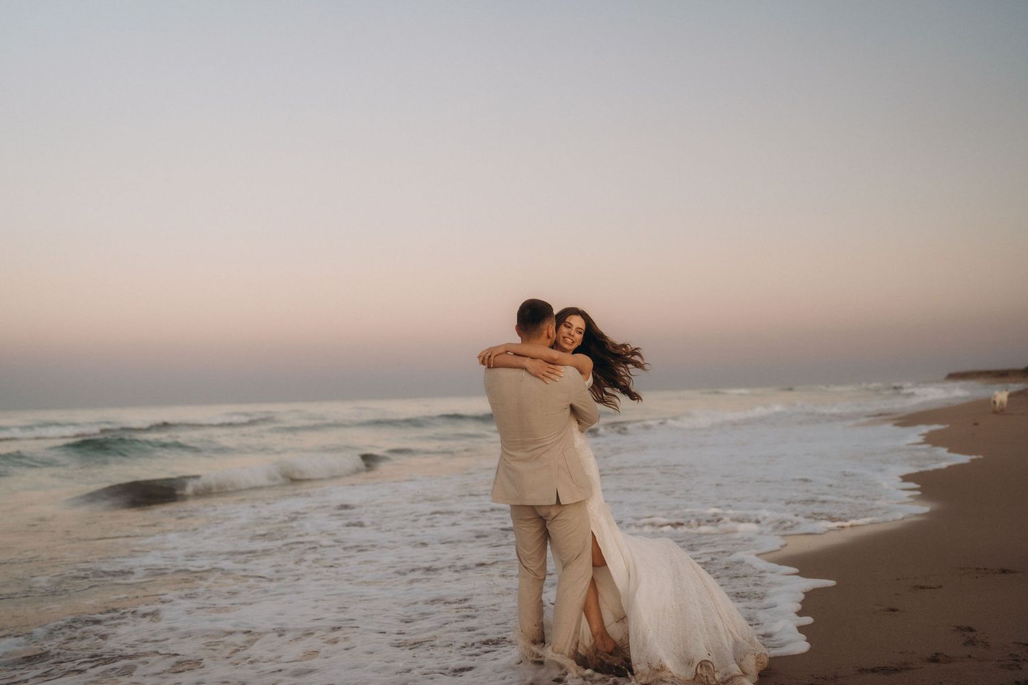 A romantic beach photoshoot captures tender moments between a couple at dusk.
