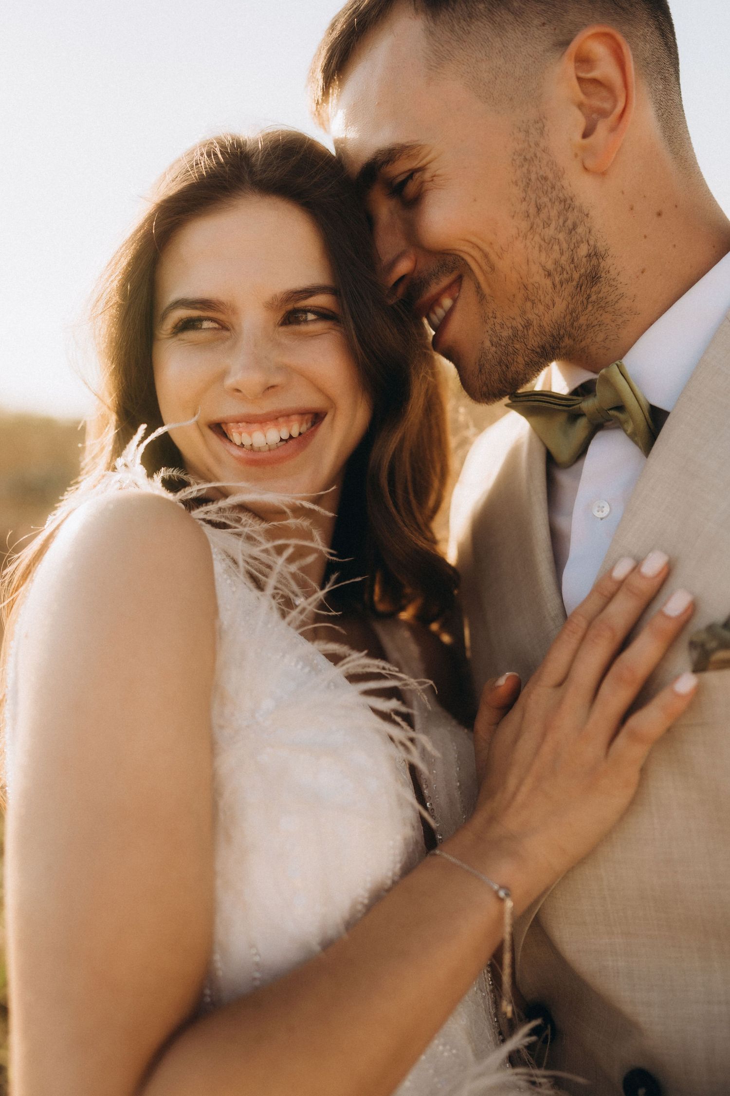 Joyful wedding couple embracing in golden sunlight.