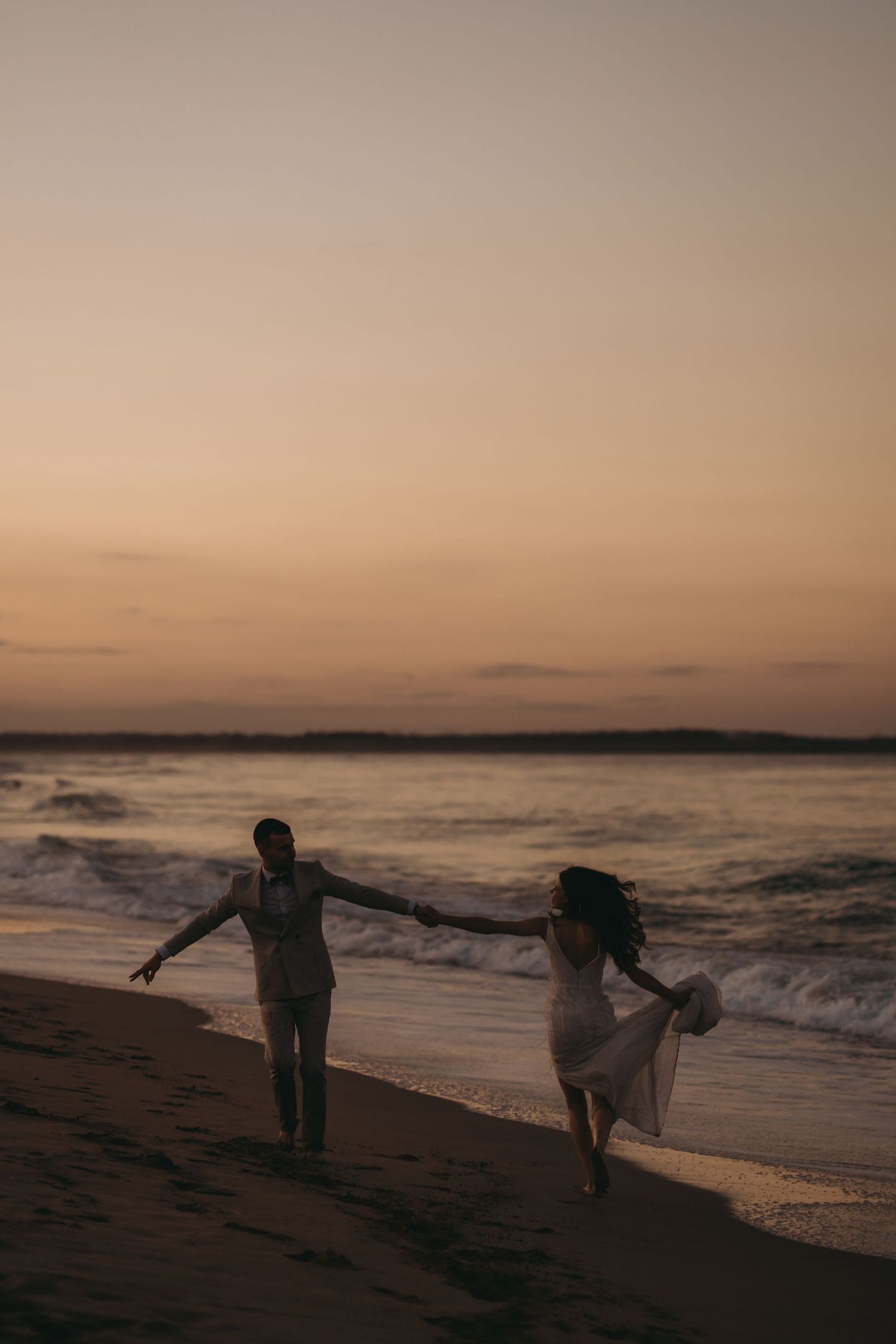 Silhouettes dance and play along the beach during sunset.