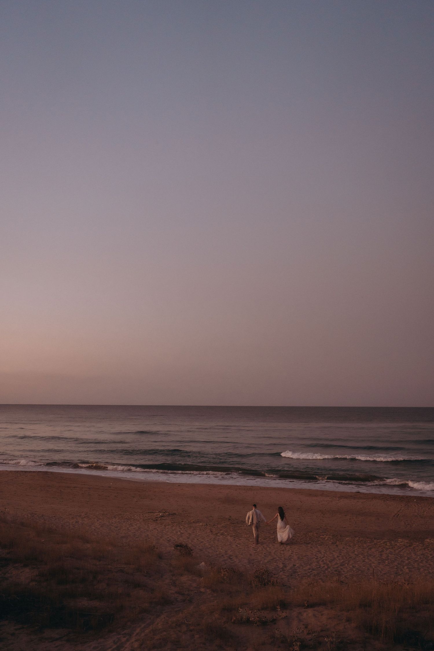 Peaceful beach scene at twilight with gentle waves rolling onto the sandy shore.