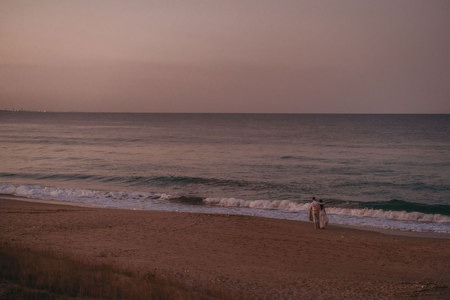 Serene oceanfront view with waves crashing on the beach during golden hour.