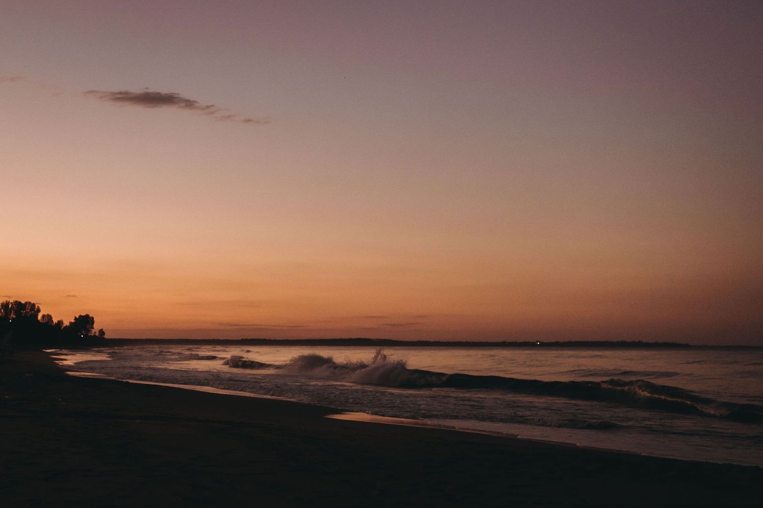 Panoramic coastal vista with dramatic clouds silhouetted against a setting sun.