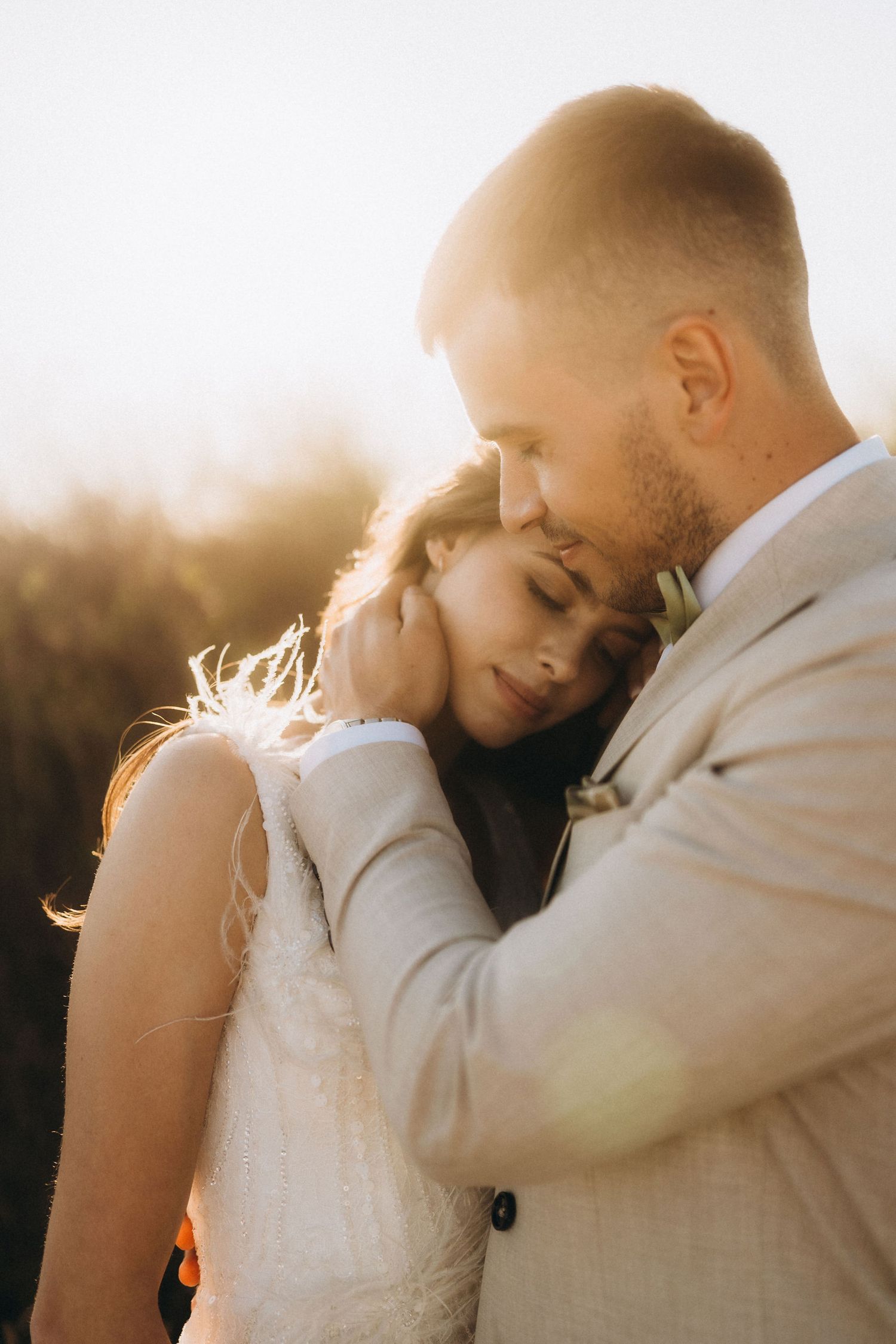 Intimate wedding portrait of a couple in warm sunset light sharing a close embrace.