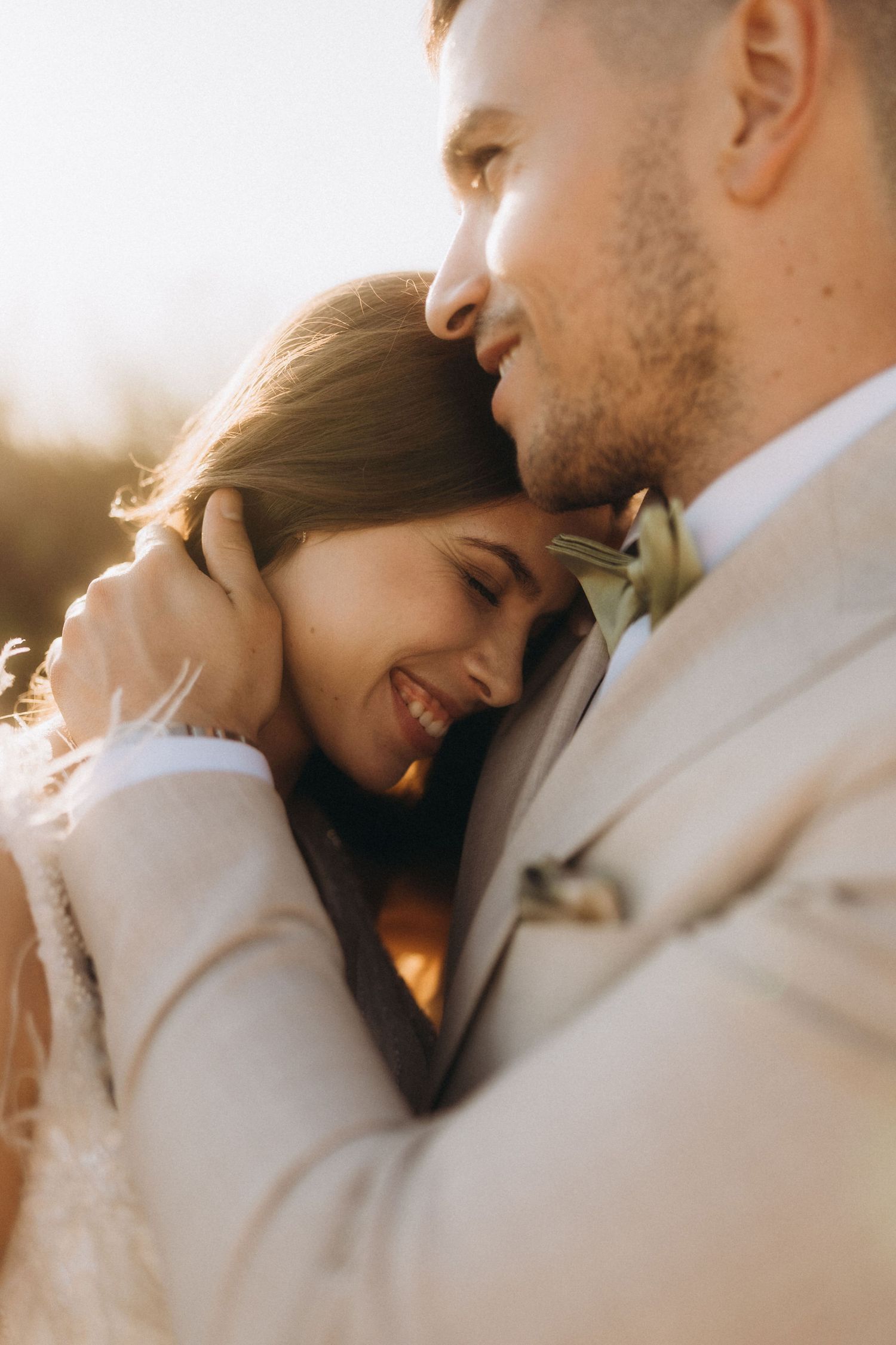 Close-up wedding photo of couple sharing a joyful moment in golden sunlight.