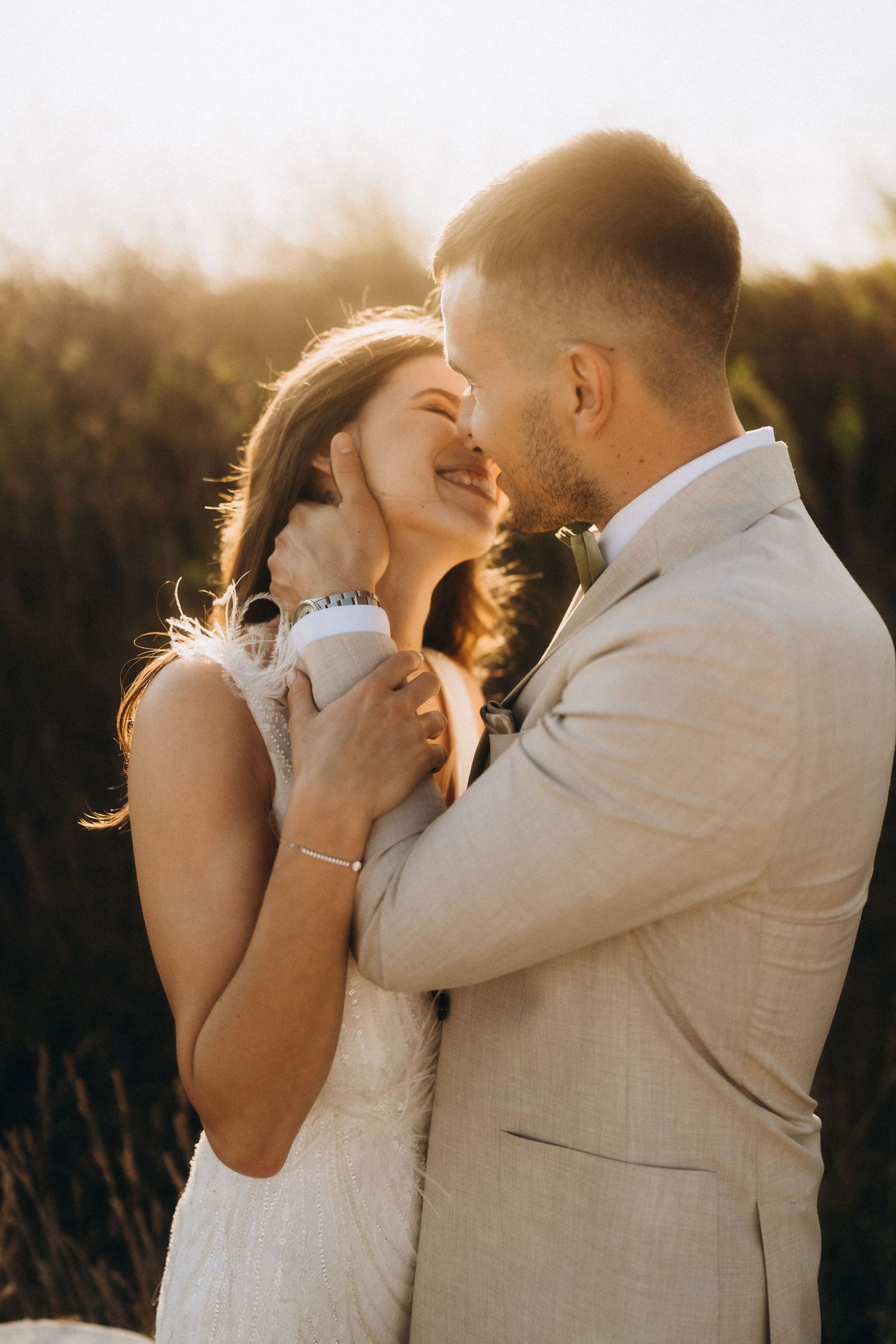 Romantic sunset portrait of newlyweds embracing in warm evening light.
