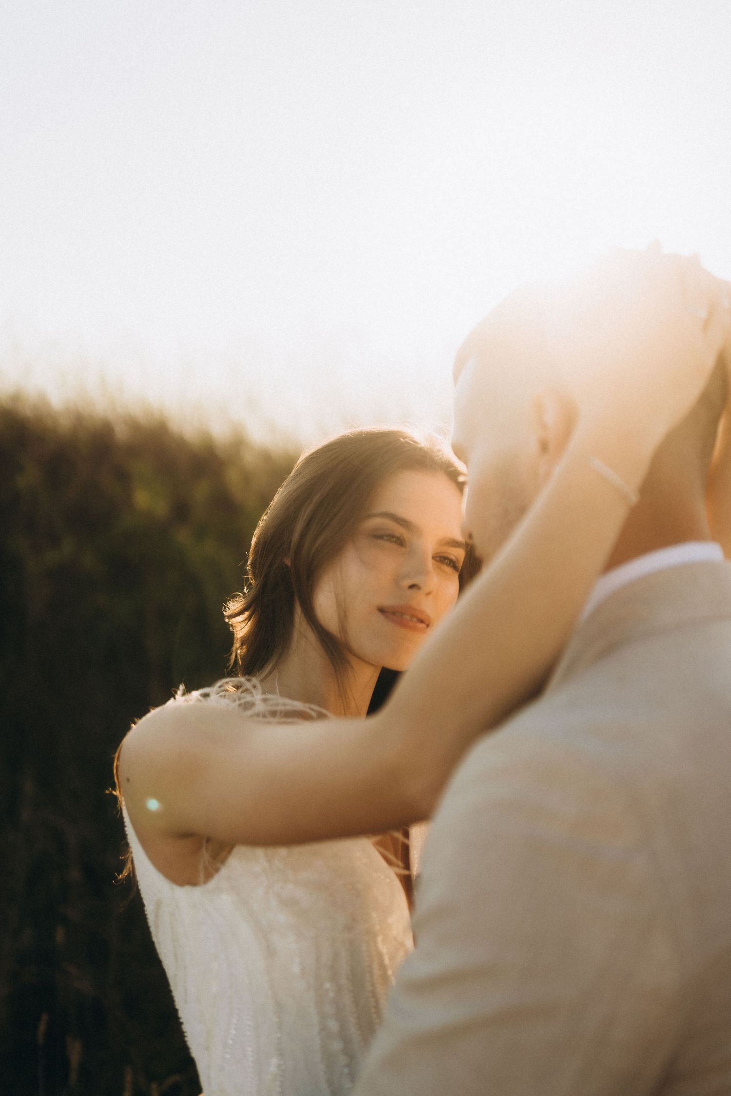 Dreamy backlit portrait of bride and groom during golden hour wedding photography.