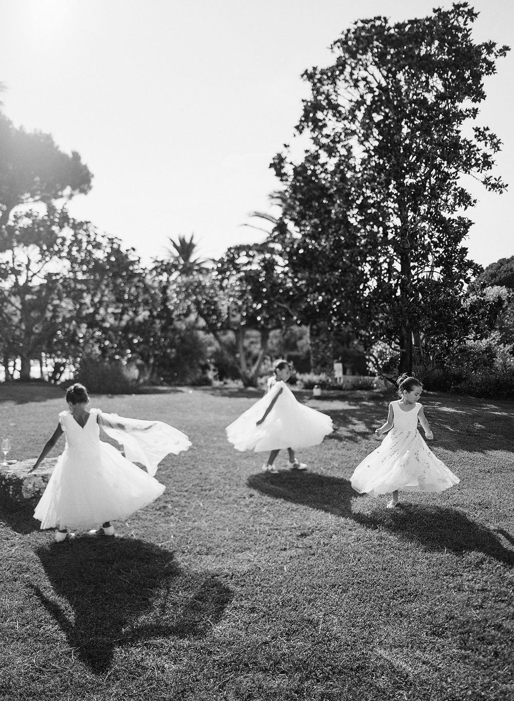 A series of black and white photos showing a person in white clothing lying on grass with flowing fabric creating artistic shapes.