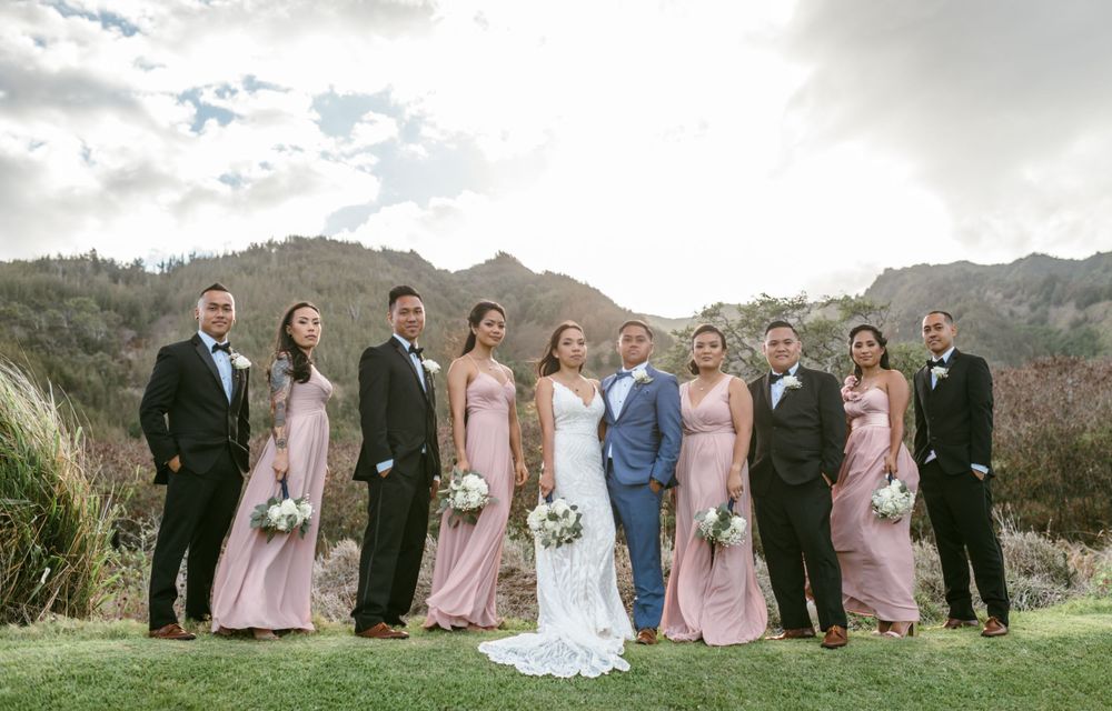 Wedding party poses for group photo on scenic mountain landscape.