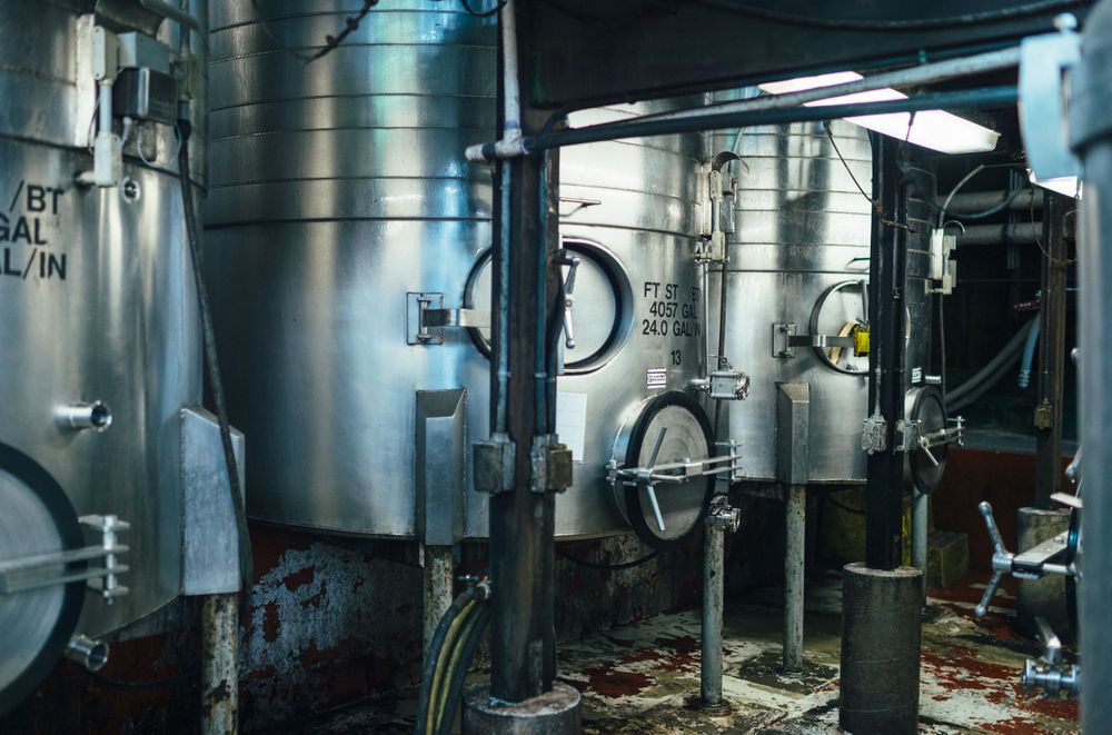 Industrial stainless steel brewing tanks and equipment in a modern brewery facility.