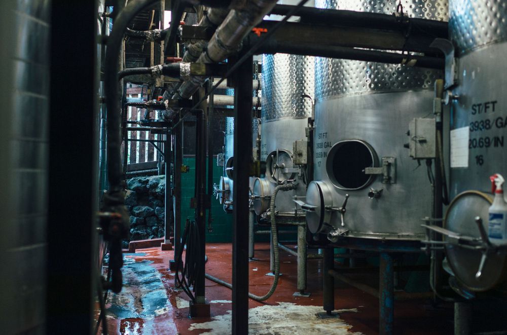 Industrial brewery equipment and tanks in a dimly lit production facility.