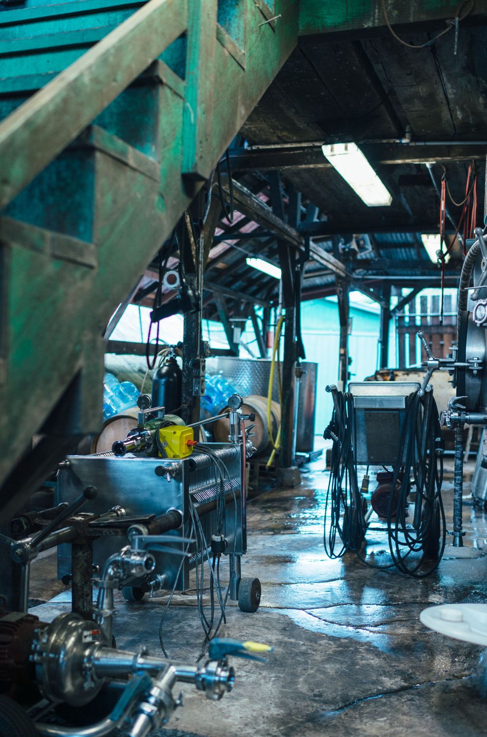 Industrial brewery equipment and tanks in a manufacturing facility with turquoise walls.