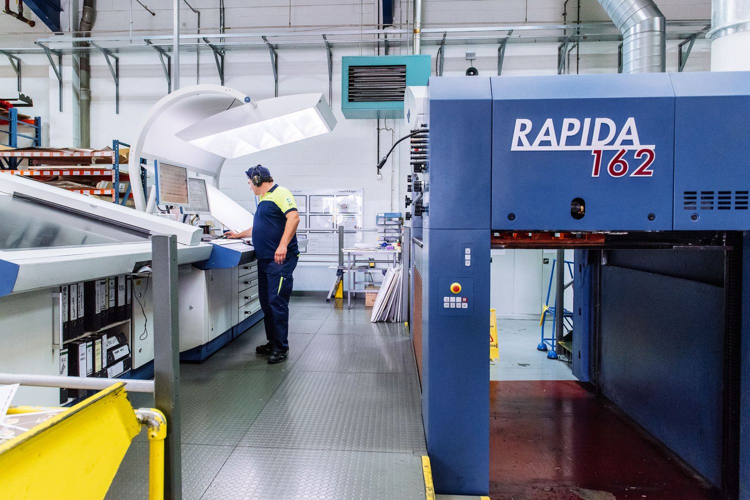 Clean industrial facility interior with blue machinery and safety markings on floor.
