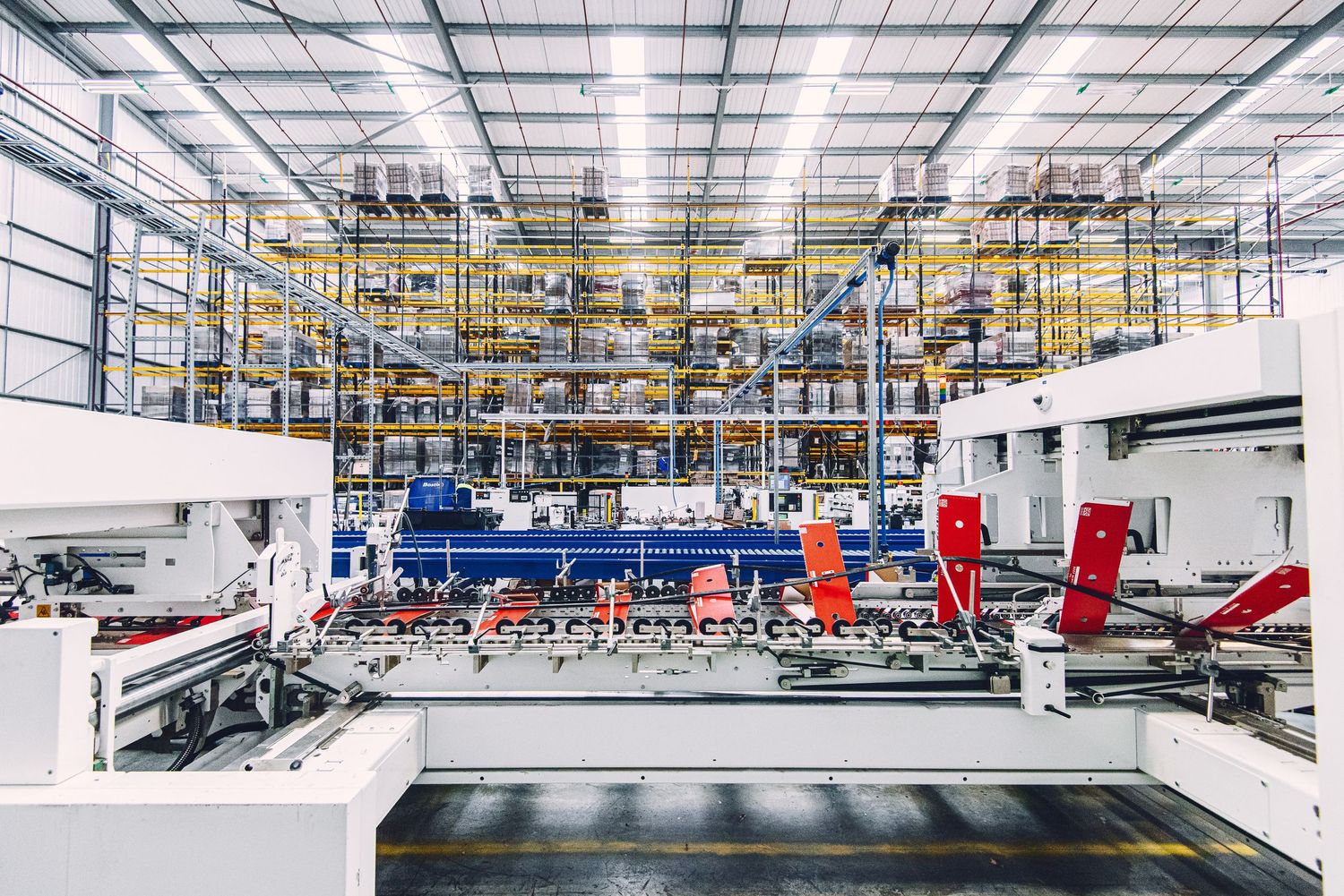 Modern industrial warehouse interior with high ceilings and organized storage racks stretching into the distance.