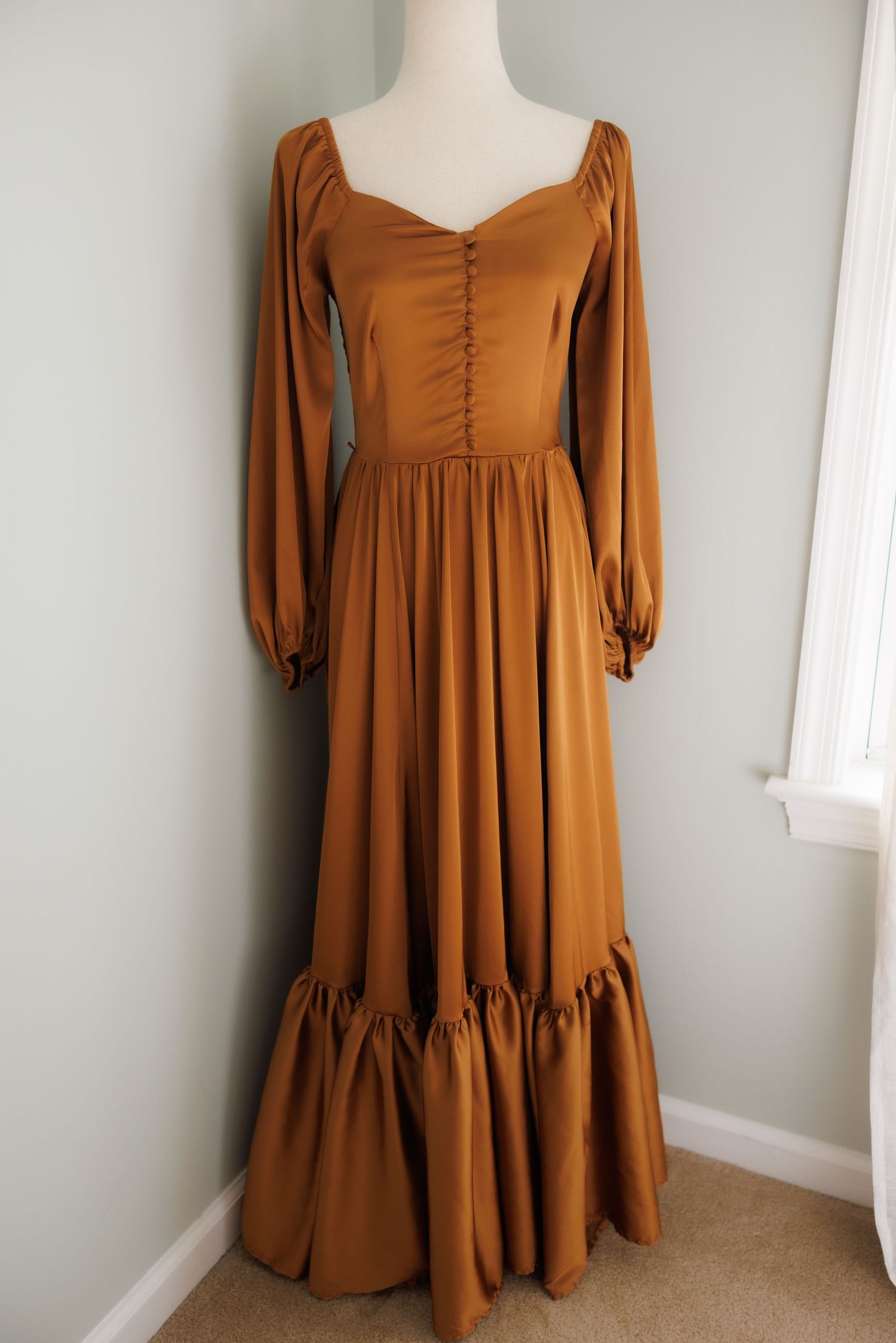 Vintage cream-colored maxi dress with puff sleeves and gathered neckline displayed on white mannequin against pale wall.