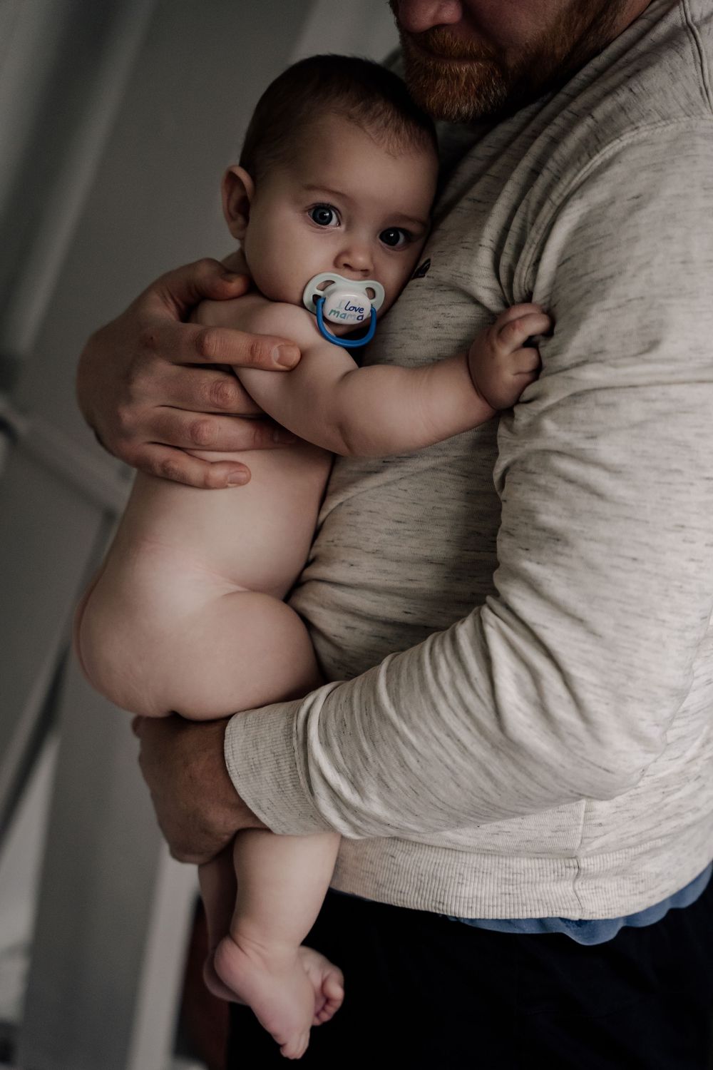 A series of intimate black and white photos showing a parent holding and comforting a baby against their chest.