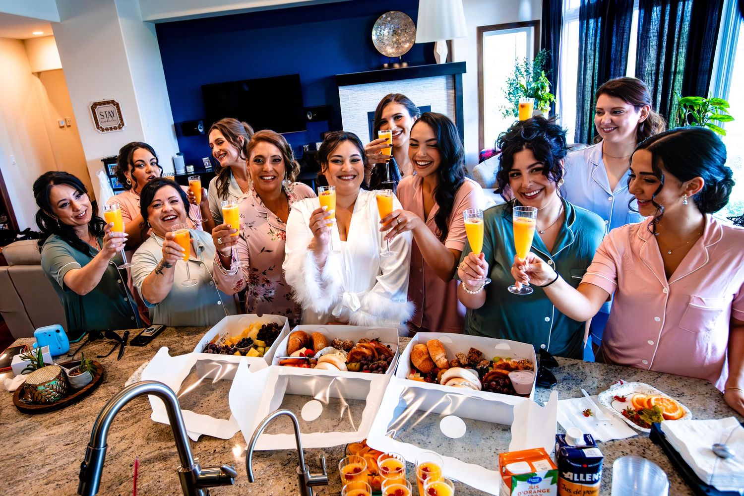 A group of friends gather around a table filled with food at a celebration party, laughing and enjoying themselves.